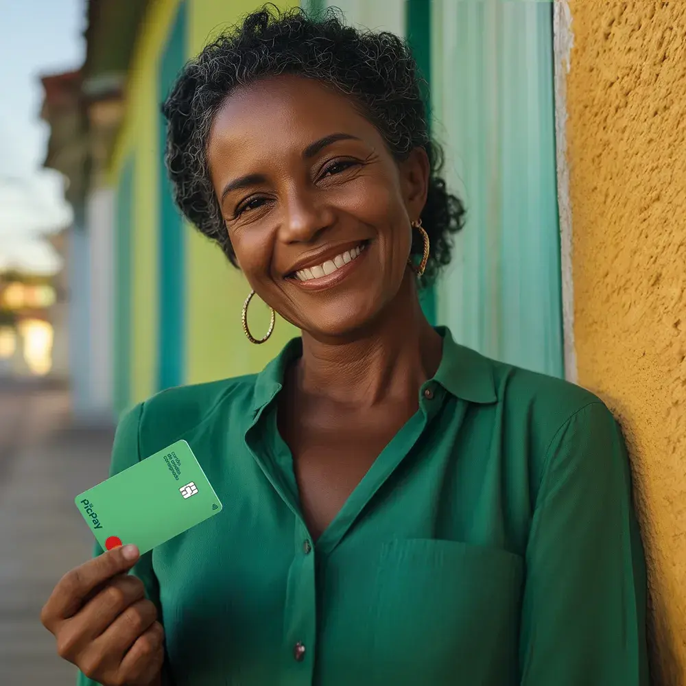 Foto de uma mulher sorridente segurando o cartão PicPay (à esquerda)