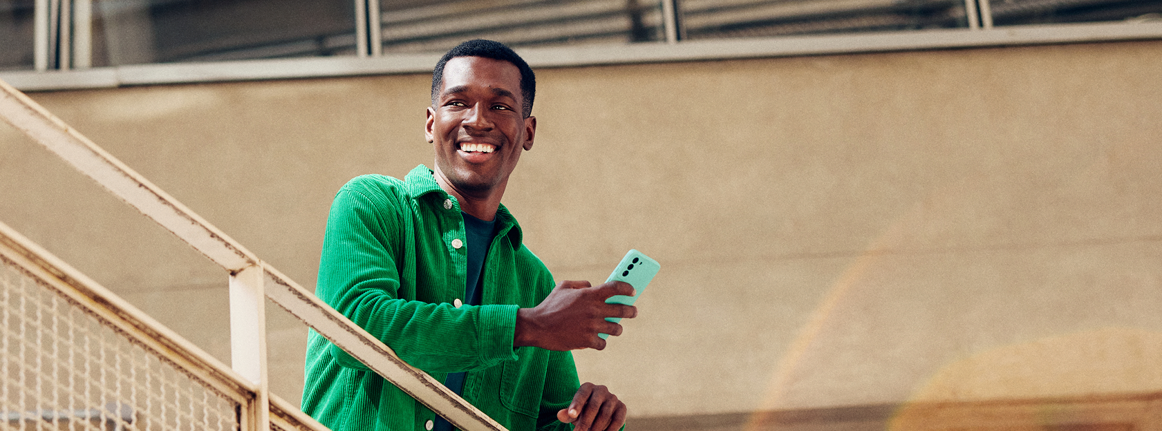 Homem na escada segurando um celular sorrindo