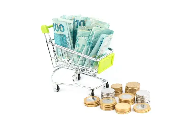 Carrinho de compras com cédulas e moedas brasileiras.