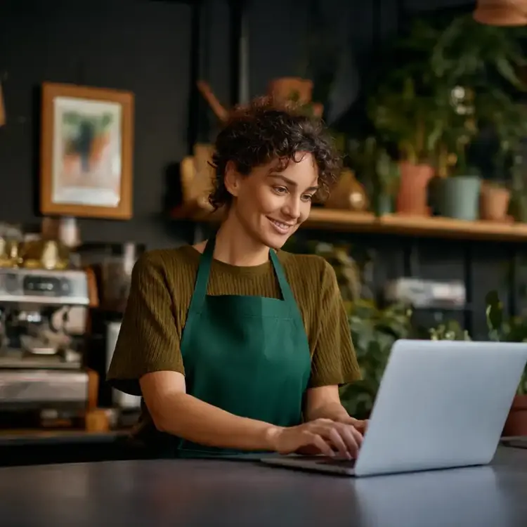 Mulher sorrindo enquanto usa um notebook.
